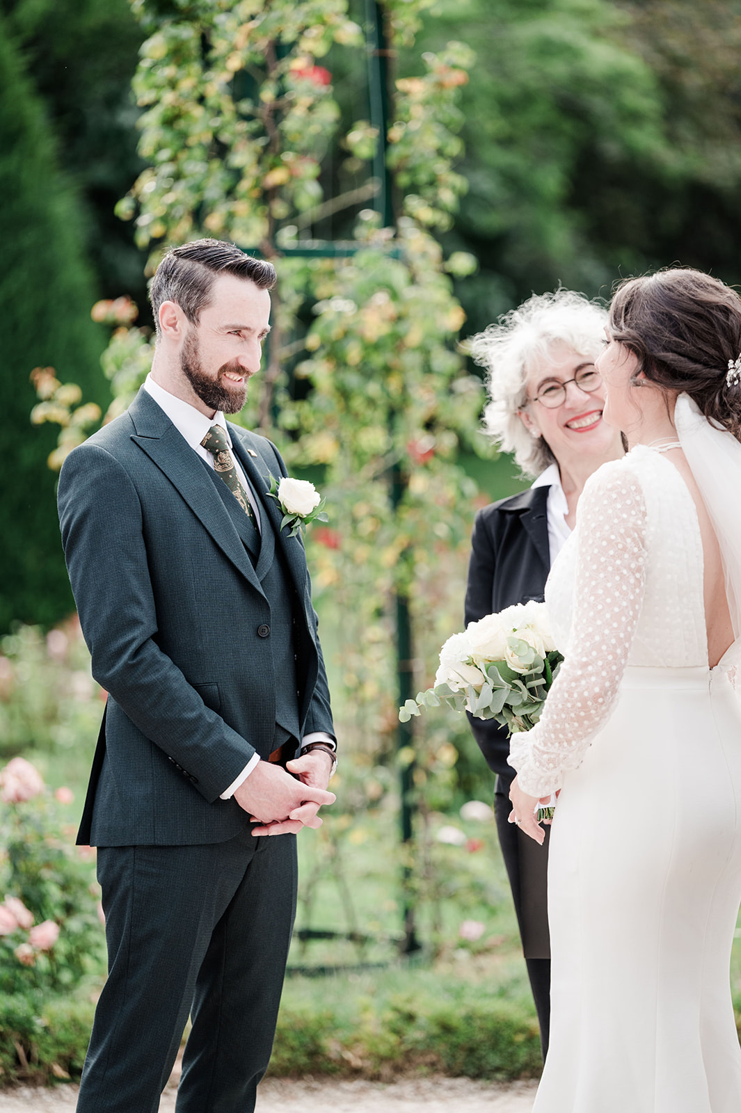 The groom laughs during the Vow exchange at parc de bagatelle The groom laughs during the Vow exchange