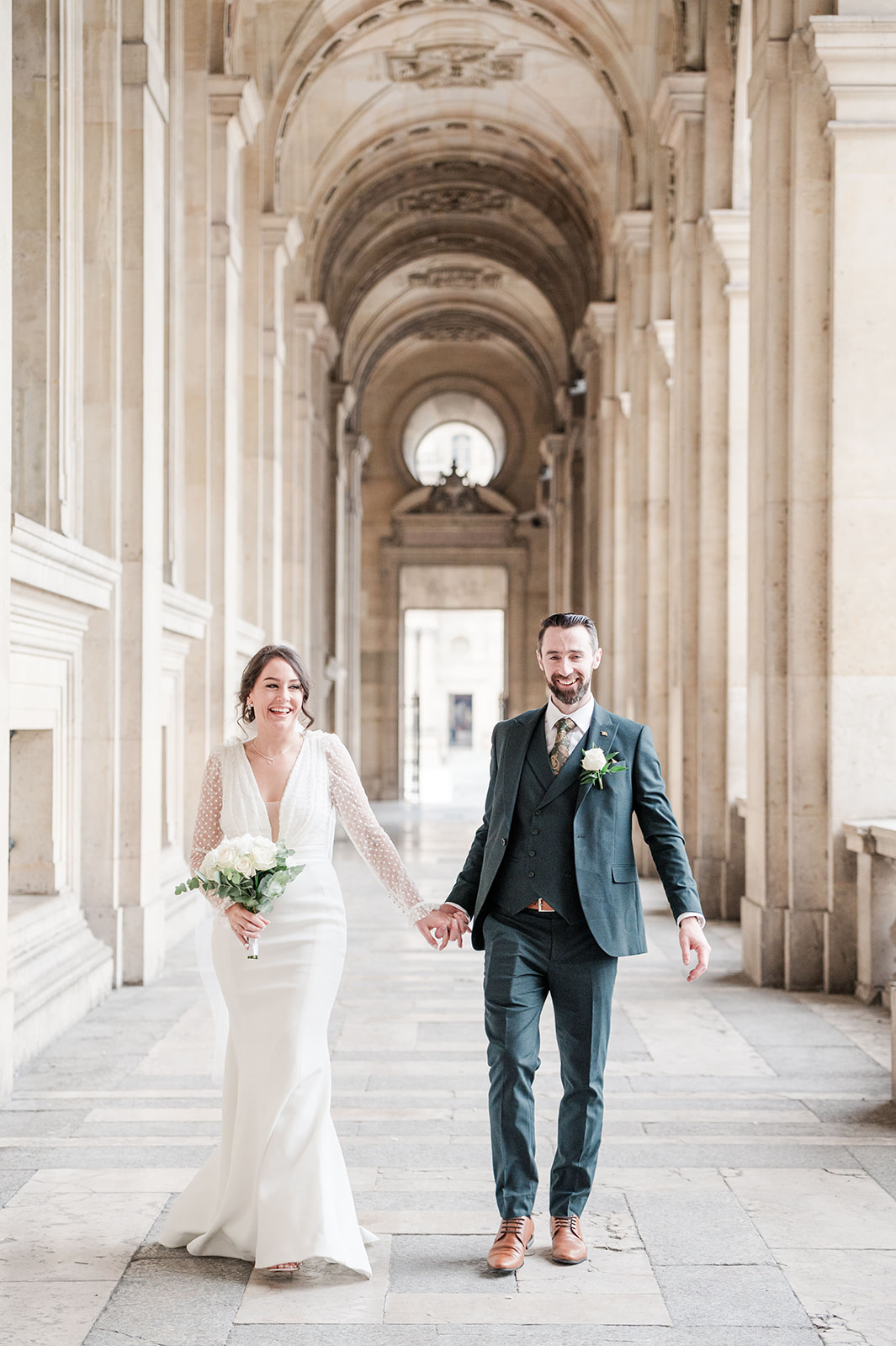 bride and groom walking the corridor at the Louvre in Paris bride and groom walking the corridor at the Louvre
