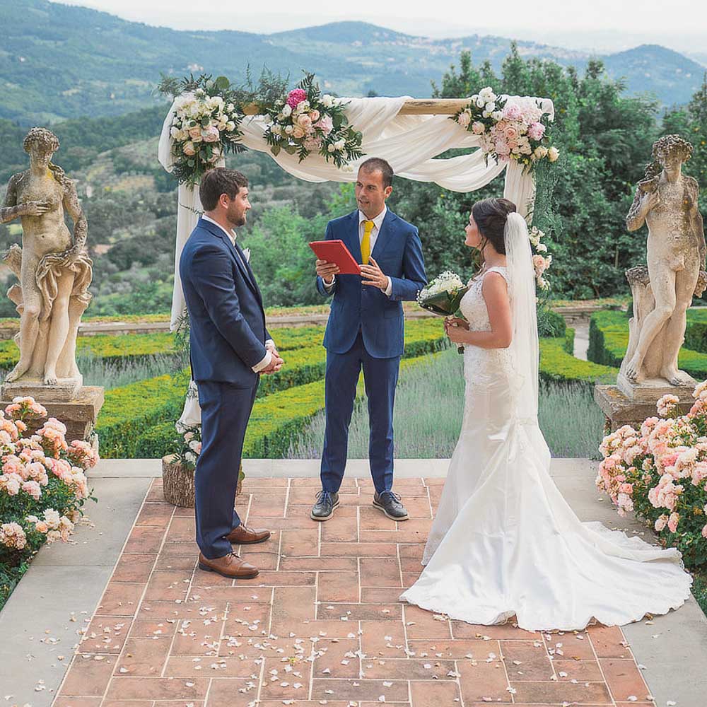 wedding in Florence-04-001 The celebrant in front of the flowers arch and starting to tell the story of the couple