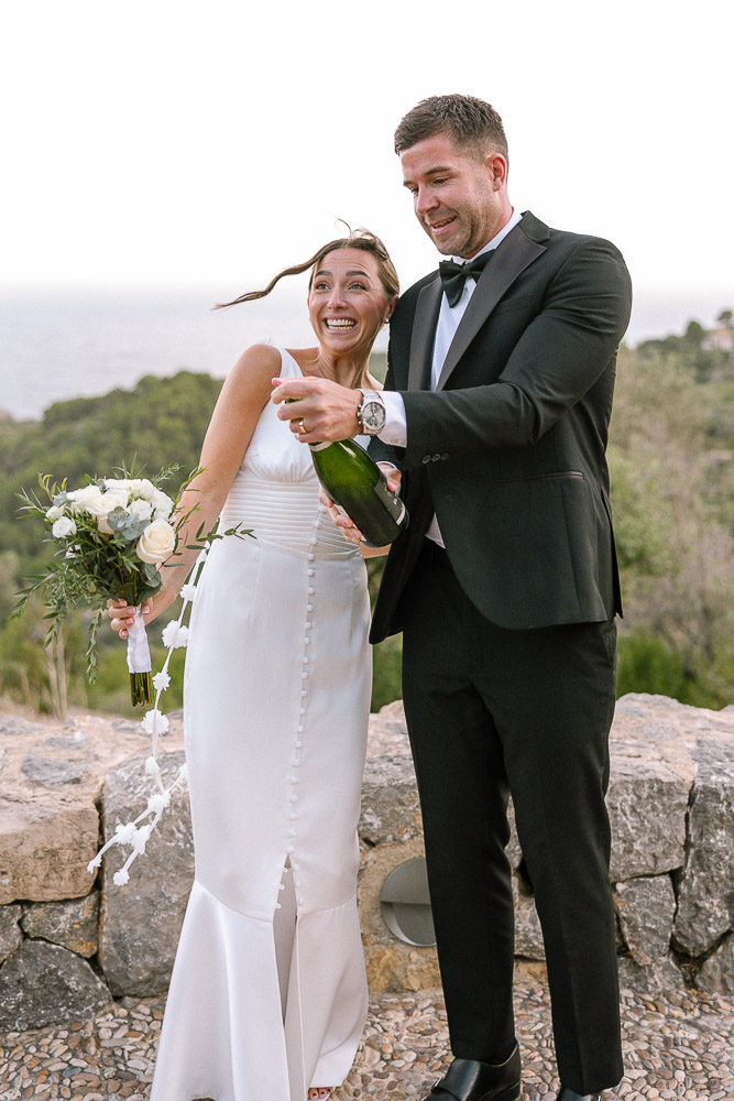 The groom opens the bottle of champagne after the ceremony in Mallorca