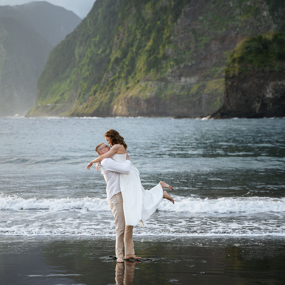 elopement in Madeira-1-005 the couple dancing and walking in the see, with a bit of fog over the trees in the background, Madeira Island