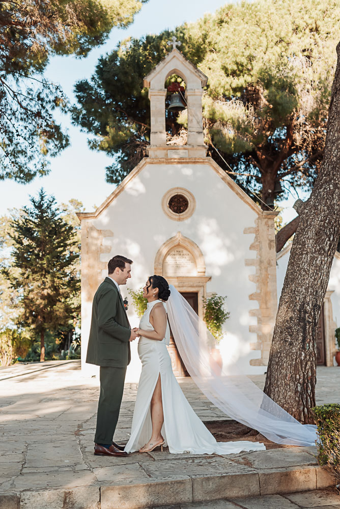 The couple facing each other in front of a little chapel in Chania, Crete