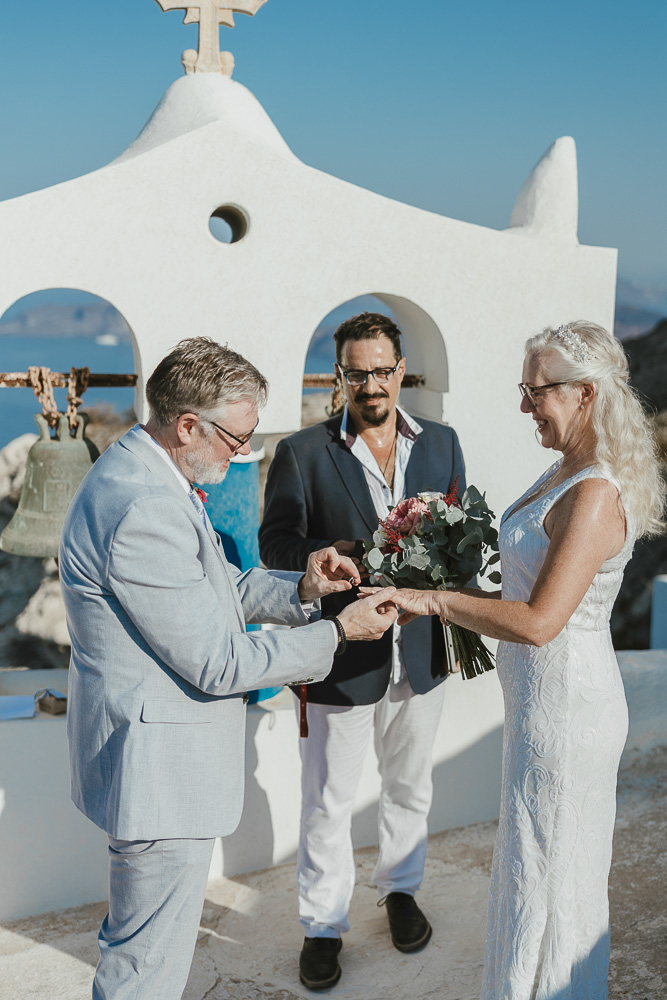 The groom slide the ring during their vows renewal in Santorini