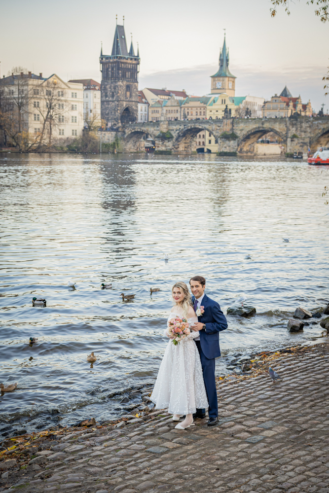 The couple facing each other on the bank river in Prague